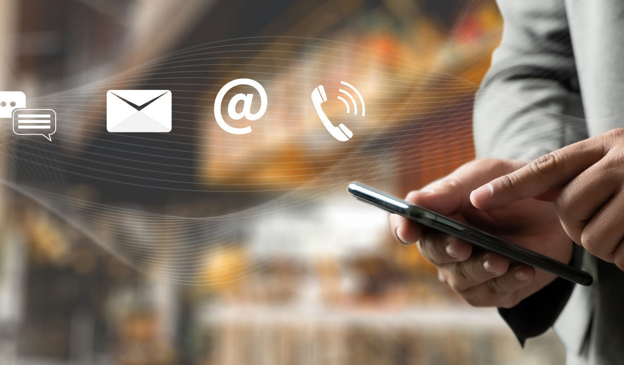 Person using a smartphone with communication icons overlayed on a blurred cityscape background